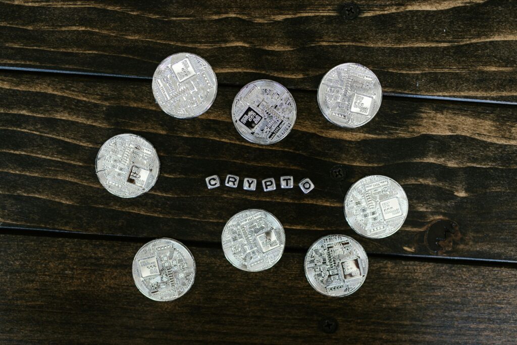 Silver cryptocurrency coins arranged on a wooden surface spelling 'crypto'.