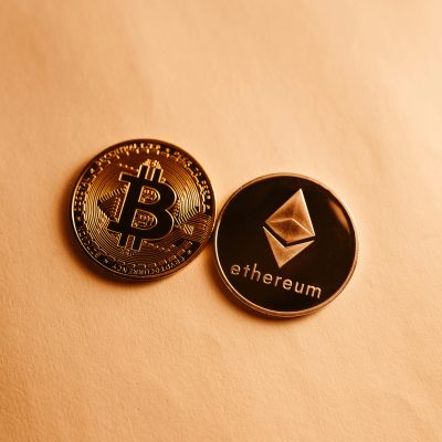 Bitcoin and Ethereum coins depicted on a soft yellow background for cryptocurrency and finance themes.