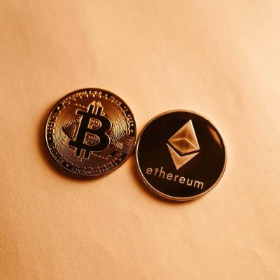 Bitcoin and Ethereum coins depicted on a soft yellow background for cryptocurrency and finance themes.