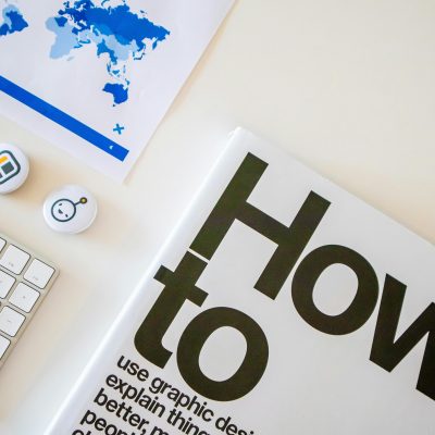 Stylish desk setup with a how-to book, keyboard, and world map on paper.